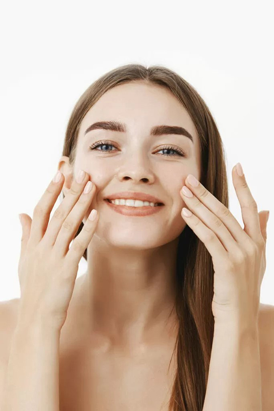 charming-relaxed-gentle-young-woman-making-cosmetological-procedure-applying-fawwcial-cream-face-with-fingers-smiling-broadly-feeling-perfect-taking-care-skin